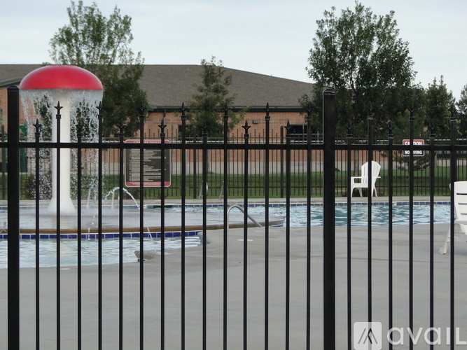 A black fence surrounds a pool with a red and white water feature in the background.