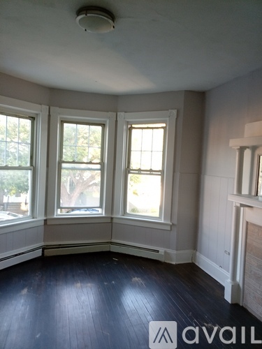 A room with a fireplace and three windows.