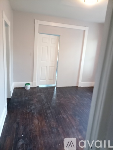 A room with a white door and a bucket on the floor.