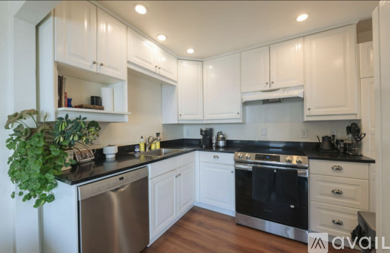 A kitchen with white cabinets and black countertops.