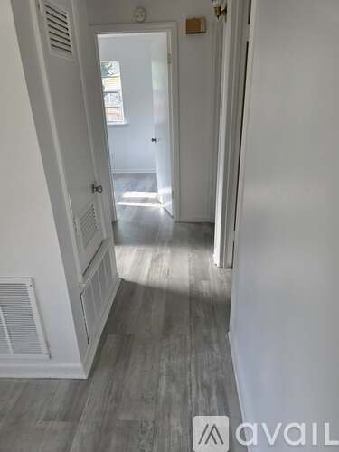 A hallway with a wooden floor and white walls.
