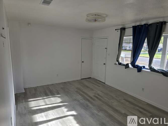 A room with a window and a door is available for rent.