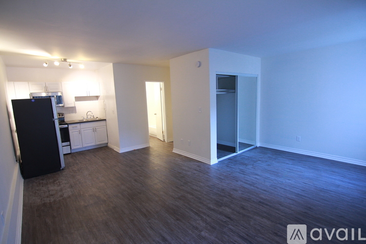 A kitchen area with a black fridge, white cabinets, and a white wall.