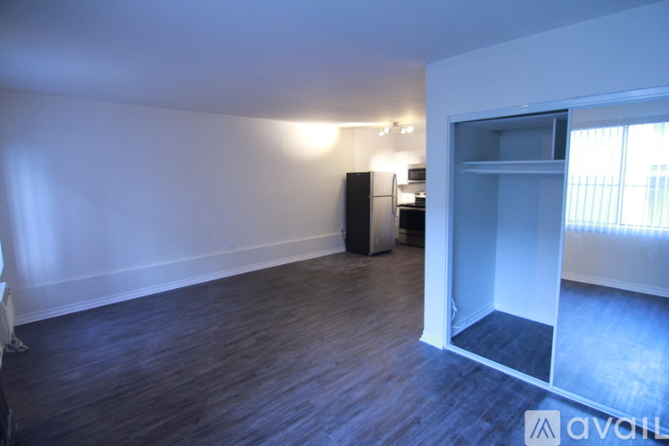 A room with a wooden floor and a white wall with a speaker and a cabinet.