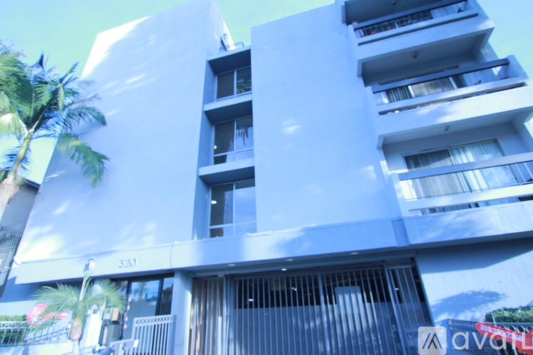 A tall white building with balconies and a black awning.