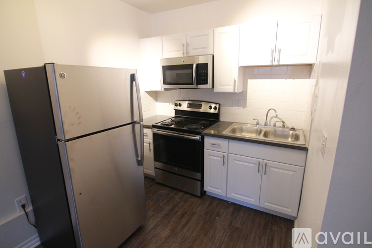 A kitchen with a refrigerator, oven, microwave, sink and cabinets.