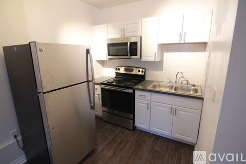 A kitchen with a refrigerator, oven, microwave, sink and cabinets.