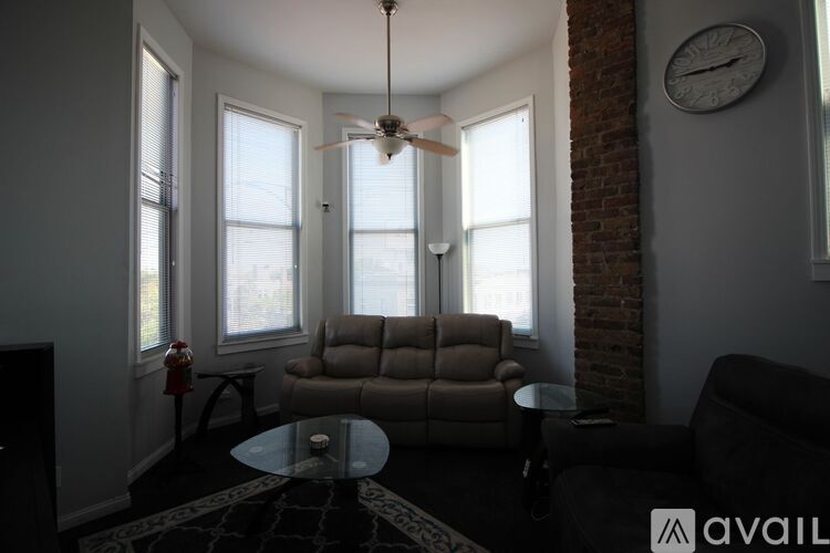A living room with a fan, a couch, and a table.