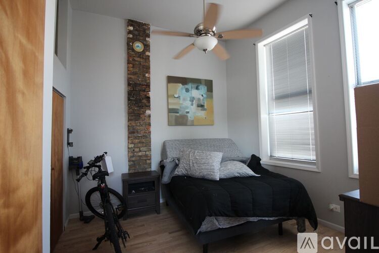 A bedroom with a bed, a ceiling fan, and a bicycle.