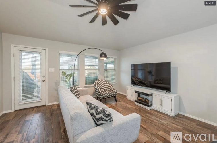 A living room with a grey couch, a television, and a ceiling fan.