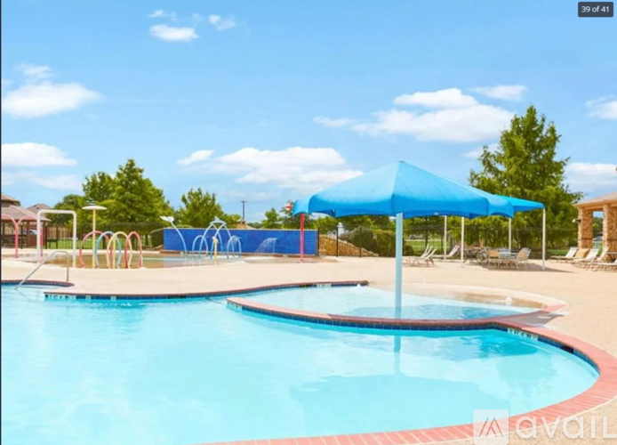 A pool with a blue umbrella and a slide in the background.