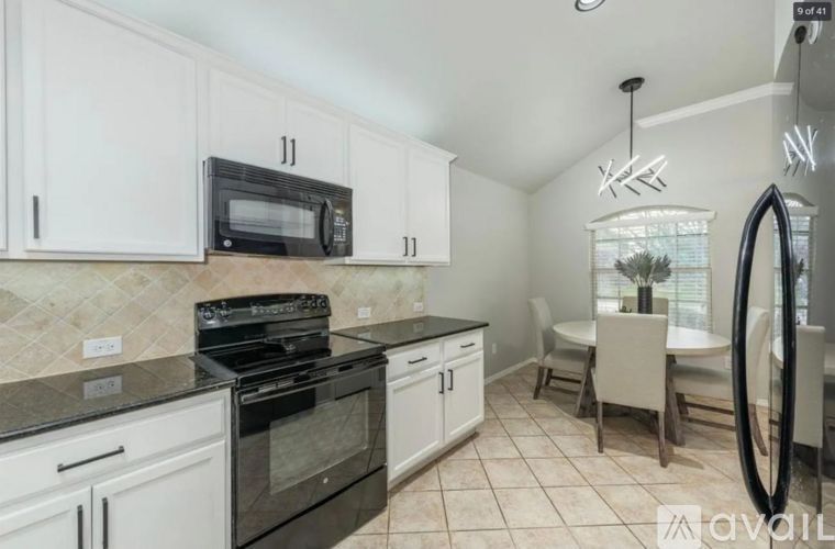 A kitchen with white cabinets and black appliances.