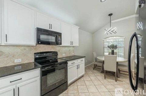 A kitchen with white cabinets and black appliances.
