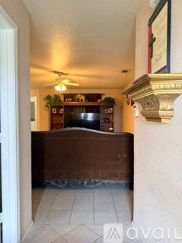 A living room with a brown couch and a ceiling fan.