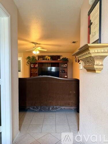 A living room with a brown couch and a ceiling fan.