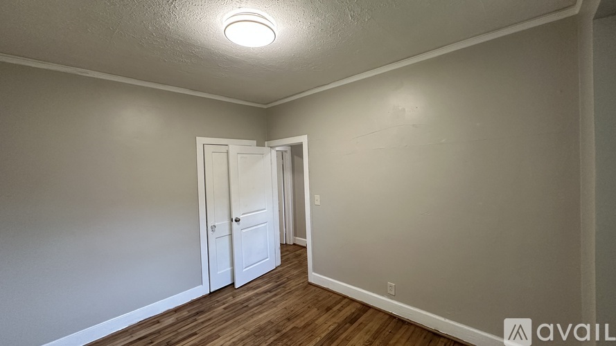 A room with a white door and wooden floor.