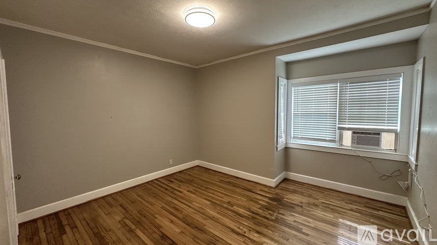 A room with wooden flooring and a window with blinds.