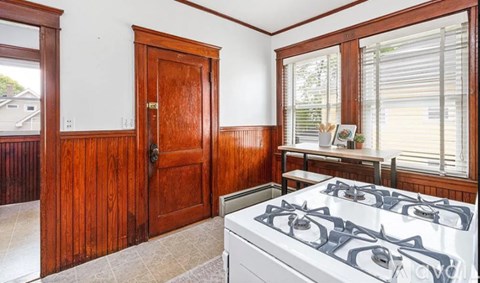 A kitchen with a white gas stove and wooden cabinets.