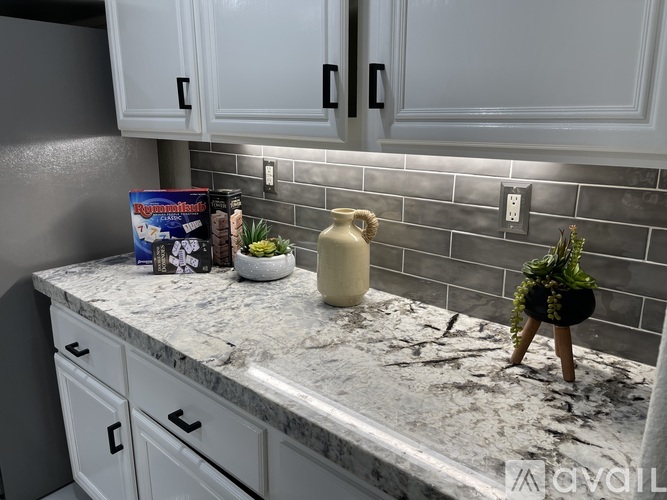 A kitchen counter with a plant, a vase, and a box of cereal.