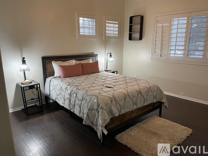 A bedroom with a large bed and a rug on the floor.