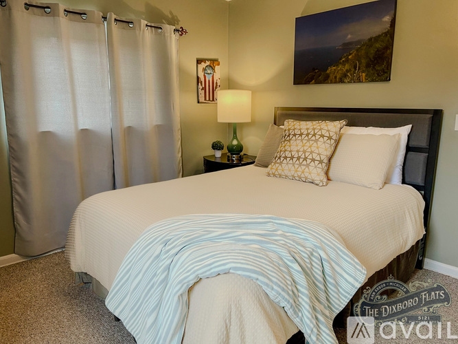 A bedroom with a bed, a nightstand with a lamp, and a painting on the wall.
