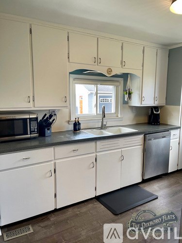 A kitchen with white cabinets and a black mat on the floor.