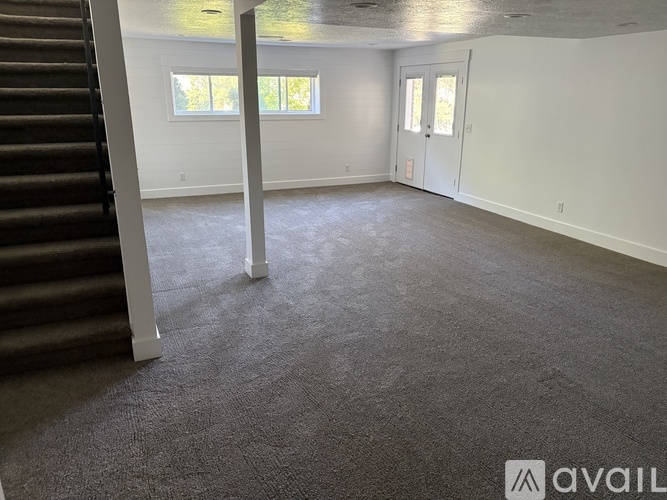 A spacious room with a staircase on the left and two doors on the right.