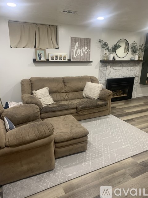 A living room with a brown couch and a fireplace.