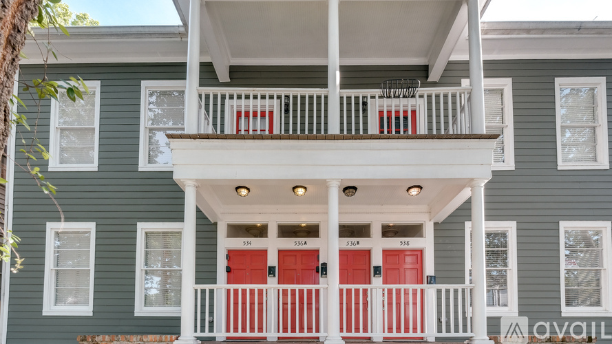 A two-story house with a balcony and red doors.