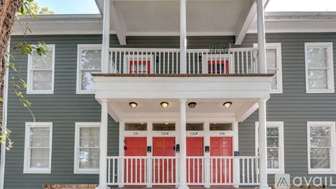 A two-story house with a balcony and red doors.