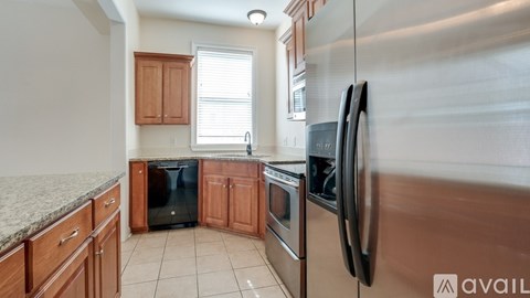 A kitchen with wooden cabinets and a stainless steel refrigerator.