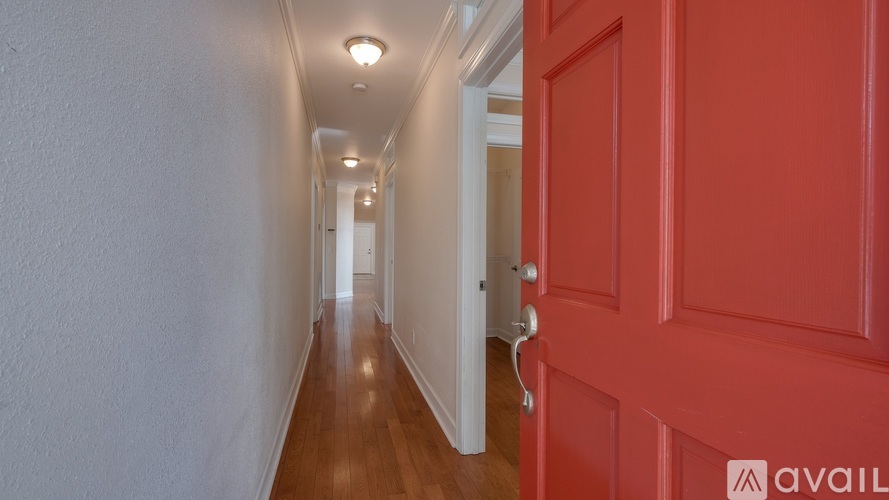 A long hallway with a red door on the right.
