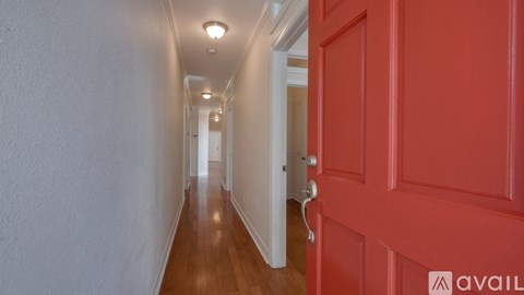 A long hallway with a red door on the right.