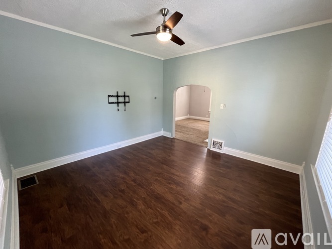 A room with a ceiling fan and wooden flooring.