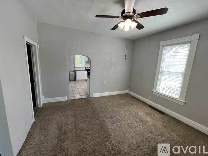 A room with a ceiling fan and carpeted floor.