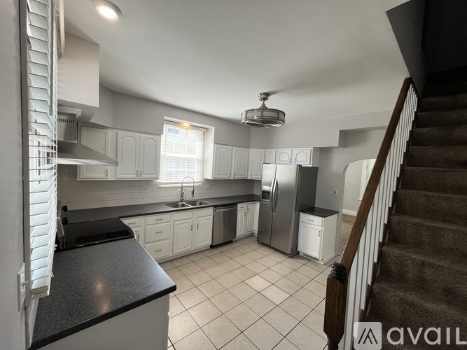A kitchen with white cabinets and a stainless steel refrigerator.