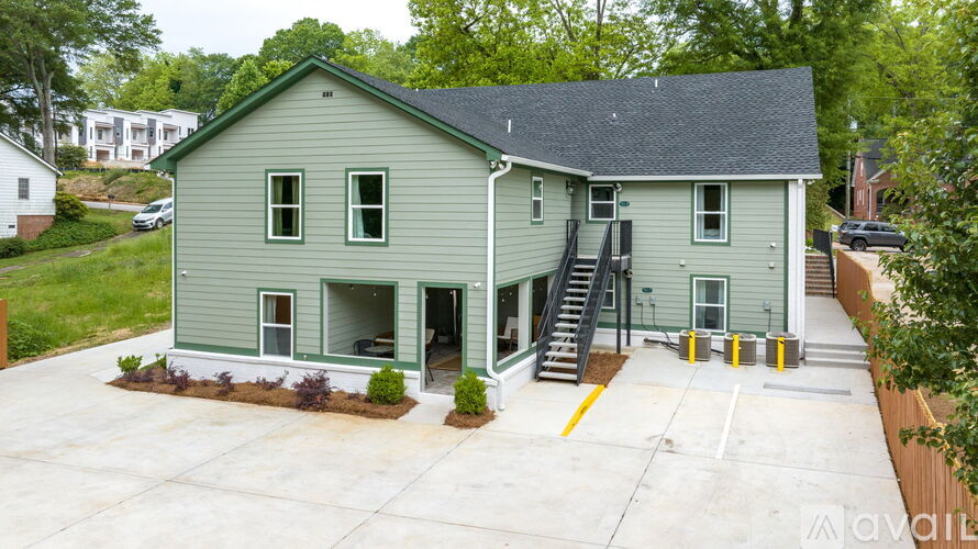 A two-story house with a green exterior and a grey roof.