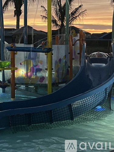A water slide in a pool with a sunset in the background.