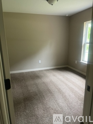 A room with a carpeted floor and a window letting in natural light.