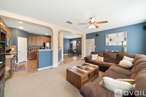 A living room with a brown couch and a ceiling fan.