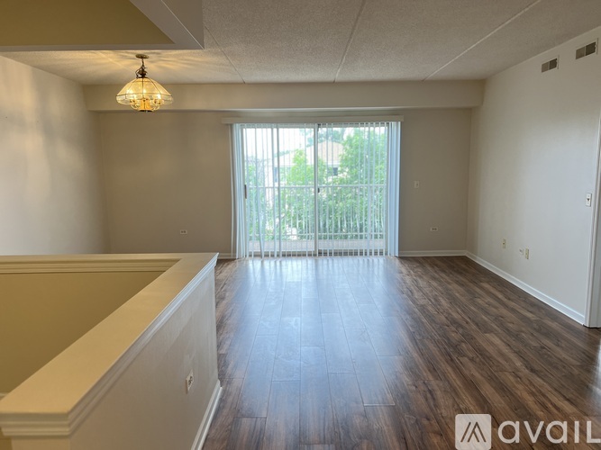 A room with wooden floors and a large window with blinds.