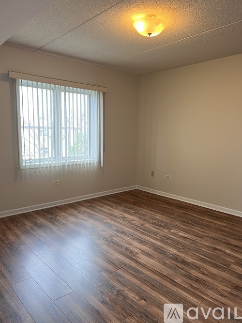 A room with wooden flooring and a window with blinds.