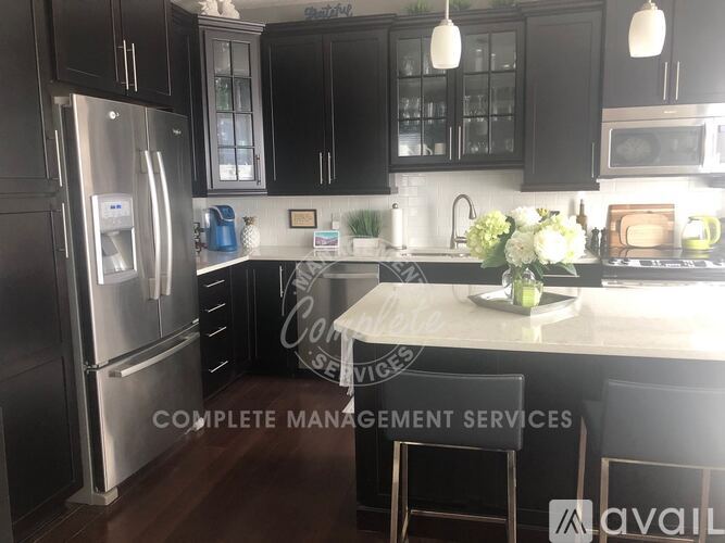 A kitchen with black cabinets and a stainless steel refrigerator.