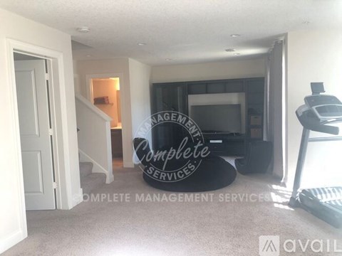 A living room with a couch and a television, with a sign that reads "Complete Management Services".