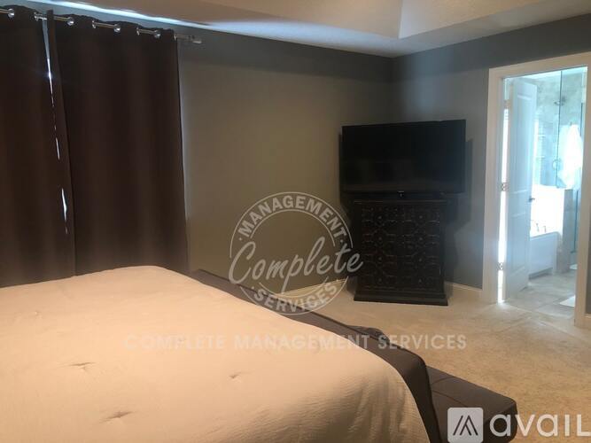 A bedroom with a bed, a television, and a sign that says "Complete Management Services".