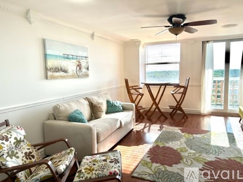 A living room with a couch, chairs, and a painting of a beach scene on the wall.