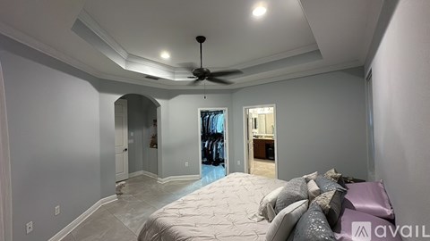 A bedroom with a large bed and a ceiling fan.