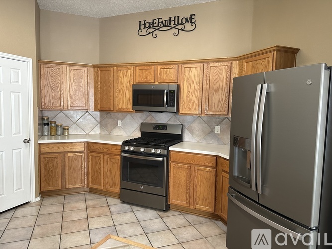 A kitchen with wooden cabinets and a stainless steel refrigerator.