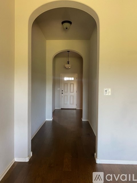 A long hallway with arched doorways and a light on the ceiling.