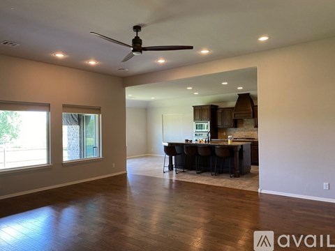 A spacious room with a dining table and chairs in the foreground and a kitchen in the background.